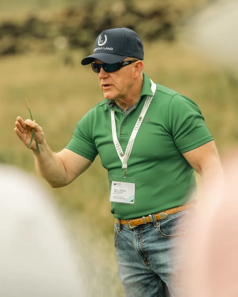 Dr Allen Williams of Libertas Land holding a blade of grass while teaching producers in the paddock